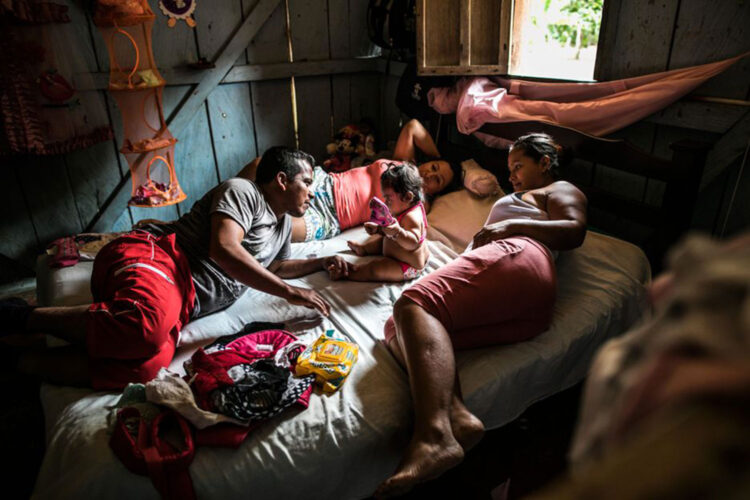 Dayana e Jairo, ambos ex-membros da Farc, deitam-se em uma cama com sua filha Andrée Nicole, na Colômbia. FOTO: © CATALINA MARTIN-CHICO/DIVULGAÇÃO/EXPOSIÇÃO RESILIÊNCIA 